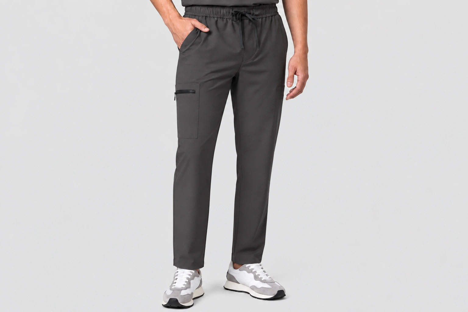 Charcoal grey scrub pants with drawstring waist, side pockets and a zippered cargo pocket worn by a male model.