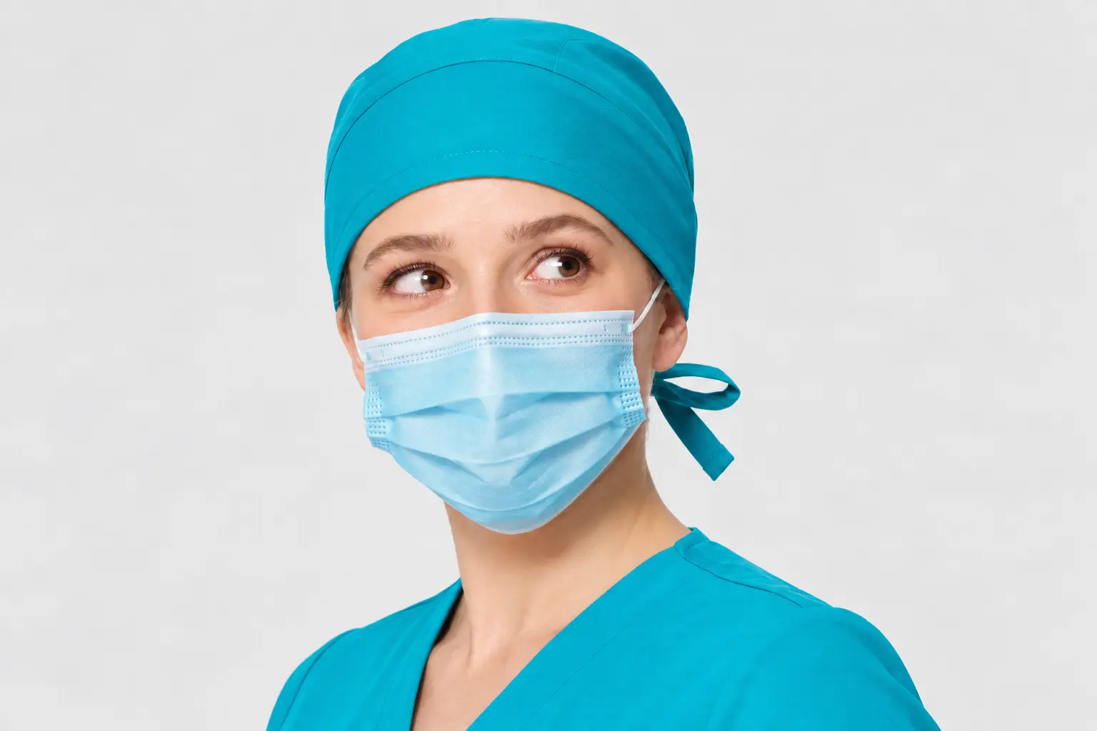 Turquoise scrub cap worn by a female medical professional with matching scrubs and a protective mask.